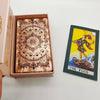 A gold foil tarot card is displayed inside a pink box, featuring an ornate design and the title The Fool.