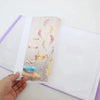 A transparent diamond painting storage album showing various small, colorful fabric pieces and embroidery samples.