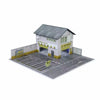 A miniature garage diorama for diecast cars featuring a small building and paved area.