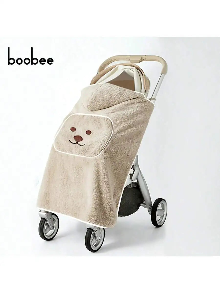 A beige baby windproof cape blanket with a dinosaur design is shown on a stroller.
