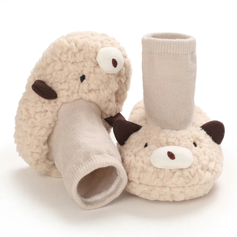 A pair of soft, beige cartoon baby booties shaped like a pig, designed for first walkers.