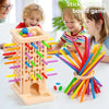 A wooden stick-drawing board game with colorful sticks and stacking towers being played by a family.