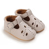 A pair of light beige lace-trimmed baby girl moccasin shoes with a bow shown from above.