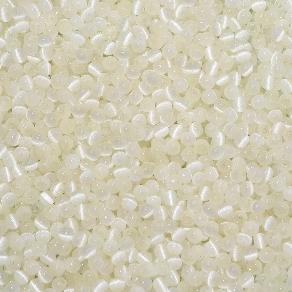 A close-up view of small, translucent white and pale yellow glass beads for jewelry making.