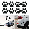 A set of black dog paw print vinyl stickers for cars, shown next to a white vehicle.
