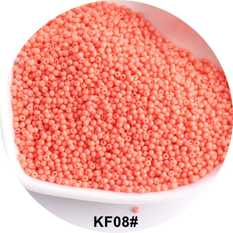 A pile of small, round, coral pink glass seed beads for jewelry and craft.