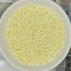 A bowl filled with small, white, rectangular polymer clay slice sprinkles for slime and DIY crafts.