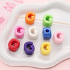 A collection of colorful acrylic letter beads shaped like the letter G in various shades and sizes arranged on a white tray.