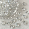 A pile of irregular square geometric glass beads for jewelry making scattered on a white surface.