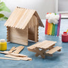 A wooden house structure made of thin wooden sticks sits on a blue surface with several loose stir sticks nearby.