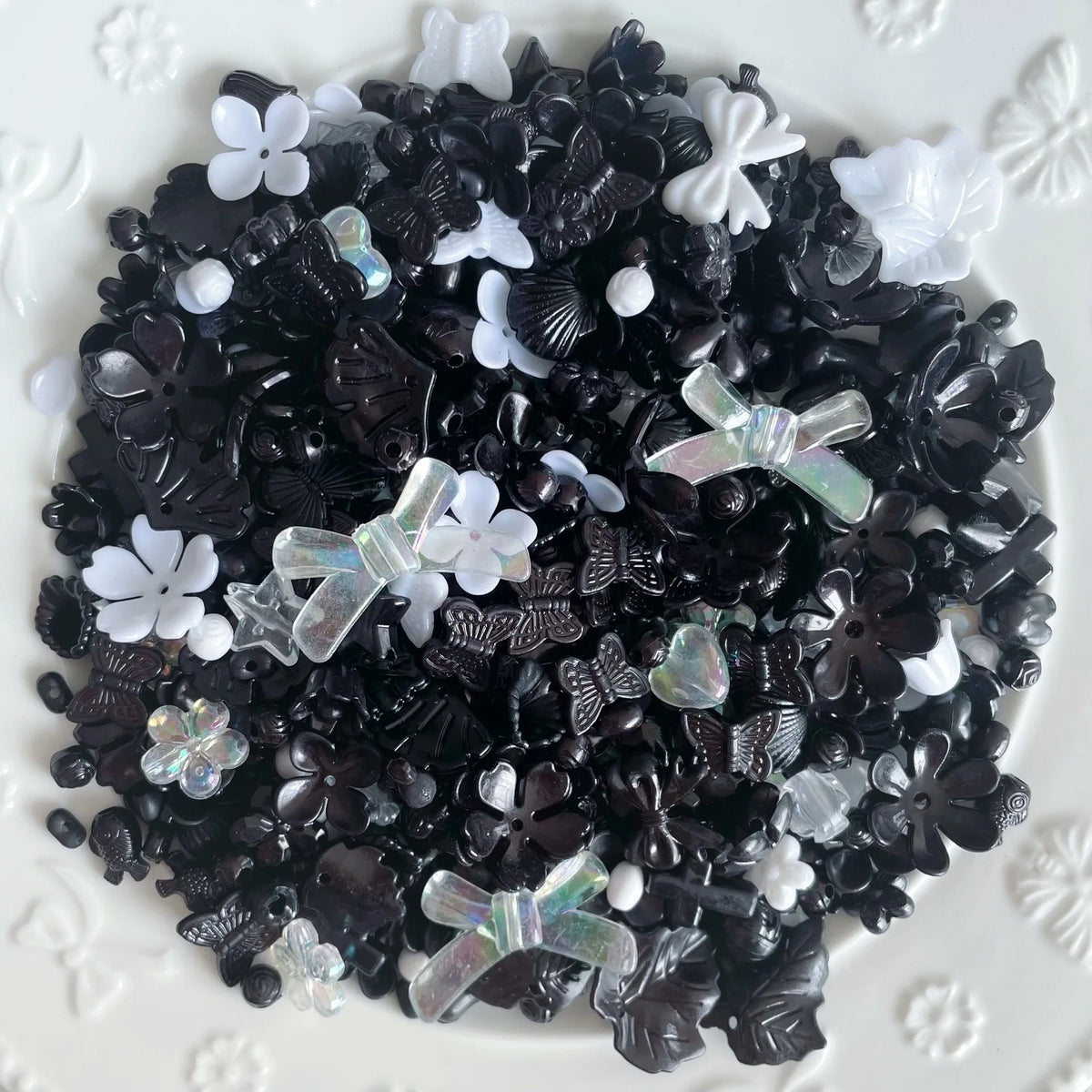 A pile of black and white acrylic bow and flower beads for DIY jewelry making