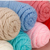 A close-up of three skeins of soft cotton blend yarn in various shades of blue, pink, and beige.
