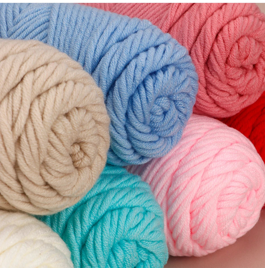 A close-up of three skeins of soft cotton blend yarn in various shades of blue, pink, and beige.