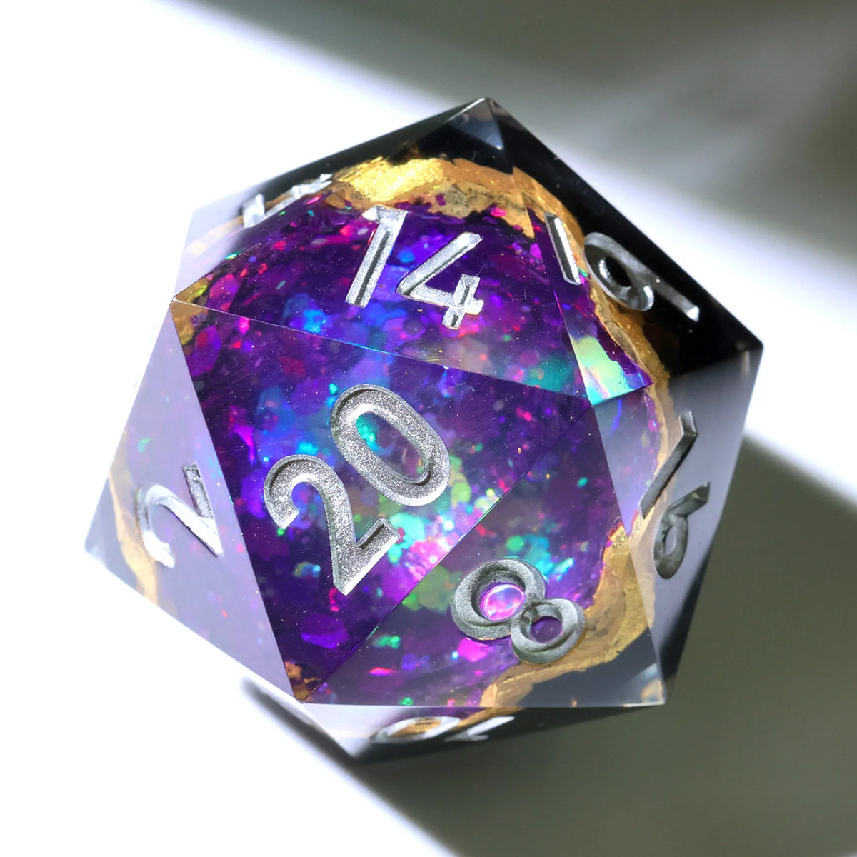 A handmade resin D20 die with a black body and a large purple and blue liquid swirl, featuring silver numbers.