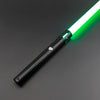 Un sabre laser noir avec une lame verte brillante, vu en diagonale sur un fond gris foncé.