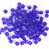 A pile of small, deep blue faceted crystal bicone glass beads for jewelry making.