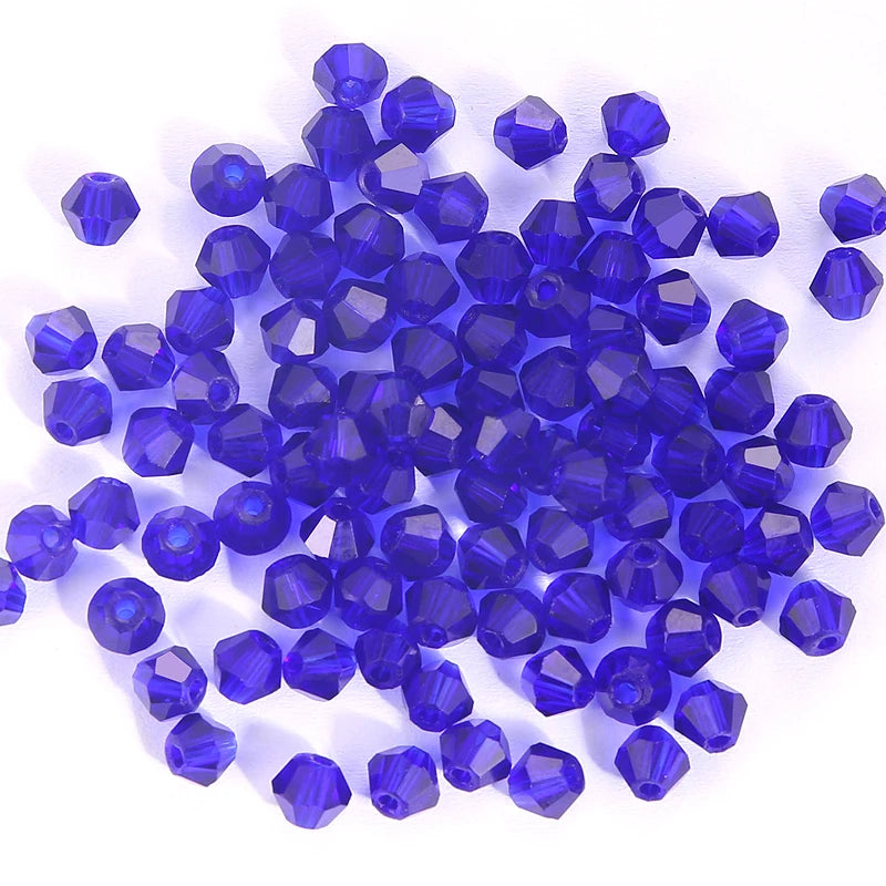 A pile of small, deep blue faceted crystal bicone glass beads for jewelry making.