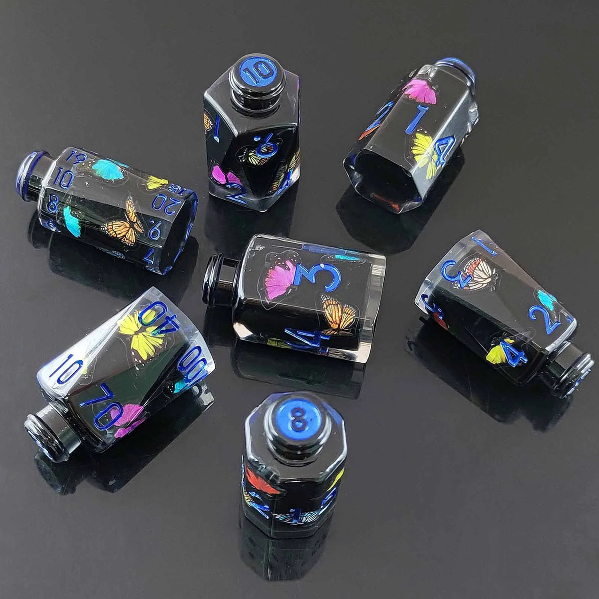A set of seven floral resin potion bottles shaped like polyhedral dice, featuring various numbers and designs.