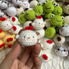 A close-up of various handcrafted crochet animal keychains, including rabbits, chicks, cats, and dogs, displayed on a white s