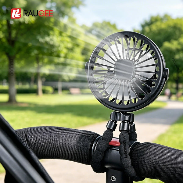 A black 360° rotating clip fan is mounted on a stroller handlebar in an outdoor park setting.