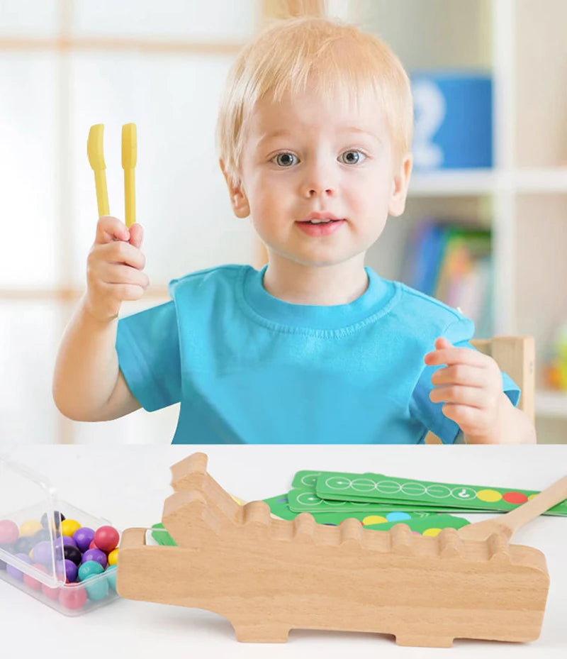 A toddler holds a wooden test tube clip beads sorting toy in front of a white table.