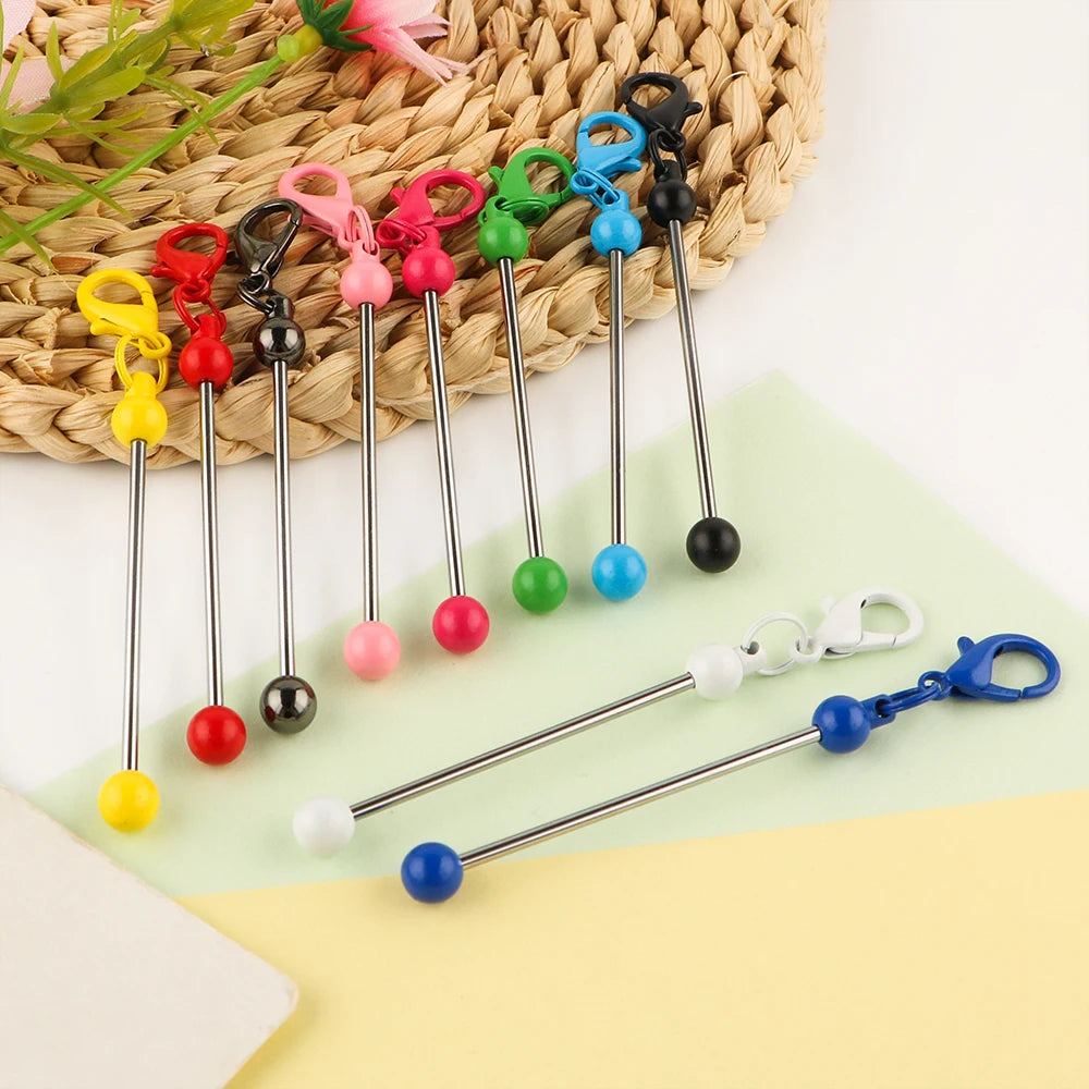A collection of metal keychain bars with lobster clasps in various colors and finishes, laid on a light background.