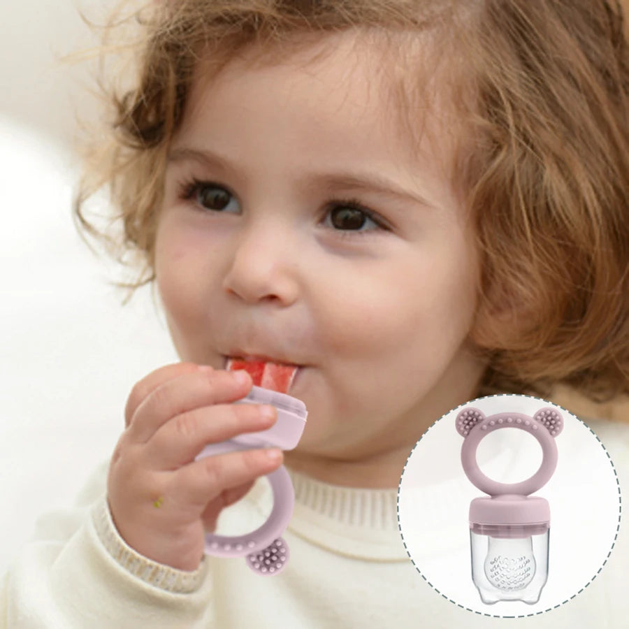 Ein Baby benutzt einen silikonigen Frucht-Flaschen-Pacifier, einen rosa Ring mit einer klaren Silikonfrucht-Einsatze.
