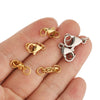 A set of gold and silver stainless steel lobster clasps and jewelry connectors displayed on a hand.