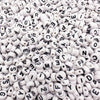 A close-up view of small white acrylic alphabet letter beads scattered in a pile.
