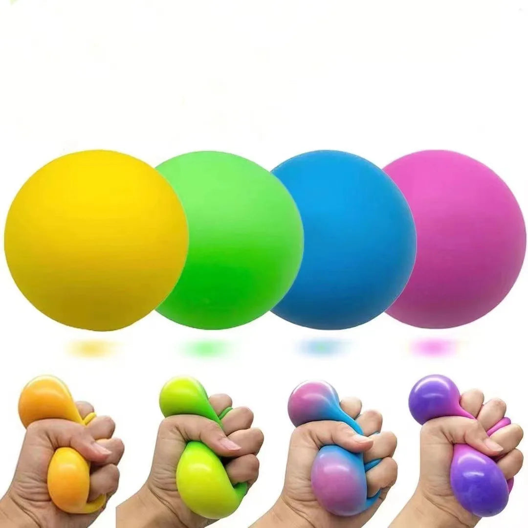A hand holds a bright yellow slow rising squishy stress ball next to various colored squishies.