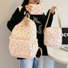 Une personne tient un sac à dos rose avec un motif de nœud blanc et une pochette assortie.