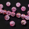 Pink gradient crystal glass beads with a golden crackle finish arranged on a dark background