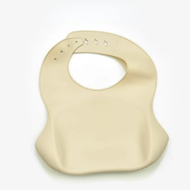 A beige soft silicone waterproof baby bib with an adjustable neck.
