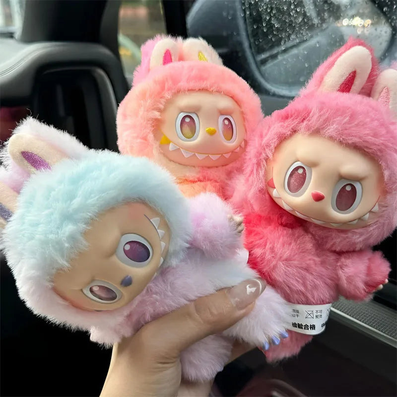 A hand is holding a pink Labubu The Monsters Big Into Energy plush doll with large ears and expressive eyes.