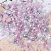 A pile of mixed resin rhinestone pearls with an AB finish in various shades of pink and silver for crafts and nail art.