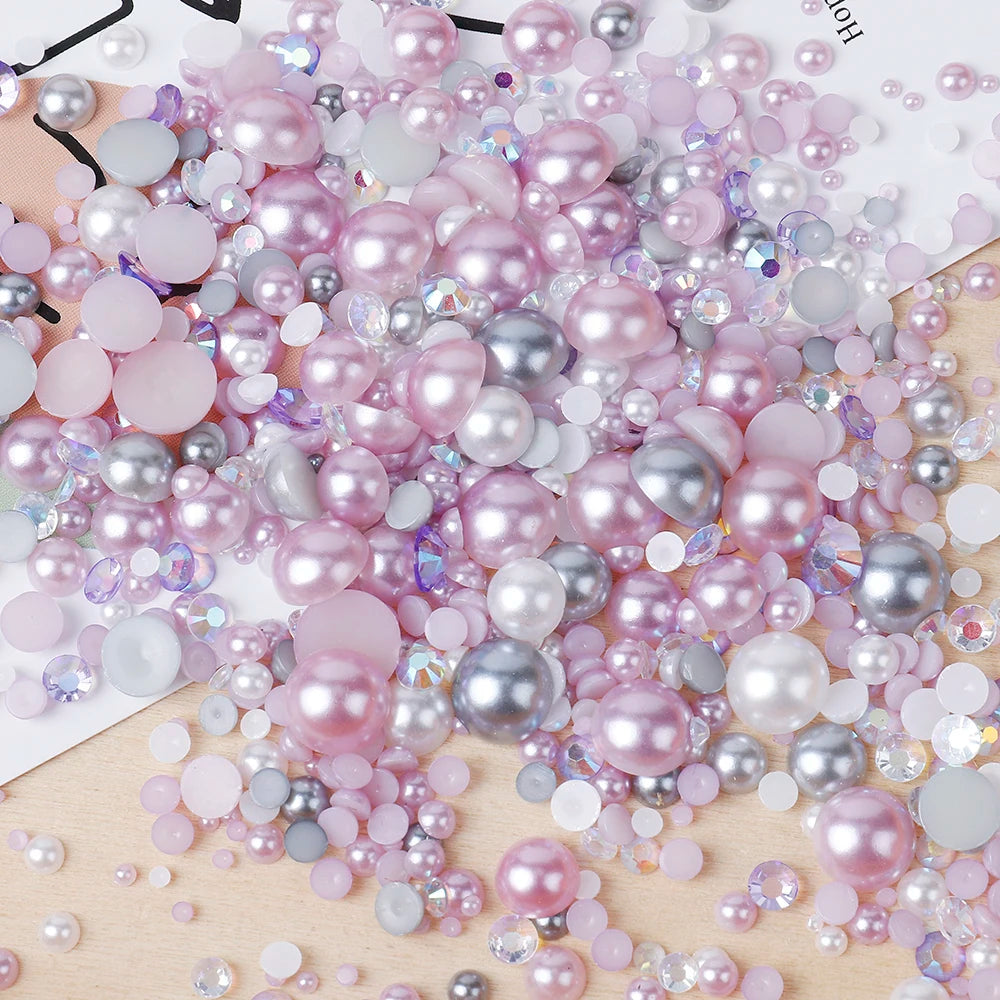 A pile of mixed resin rhinestone pearls with an AB finish in various shades of pink and silver for crafts and nail art.