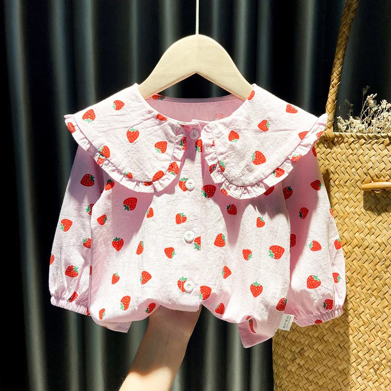 A pink baby girl long-sleeve shirt with a strawberry print displayed on a wooden hanger.