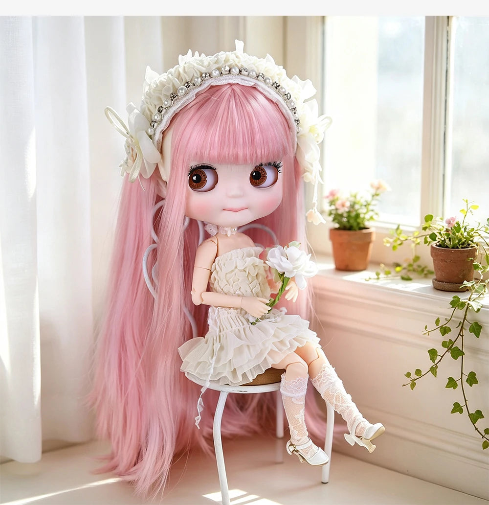 A pink hair fashion doll with white floral crown and dress sitting on a white stool near a window.