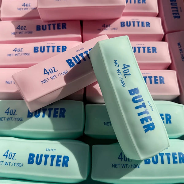 A collection of pink and light blue butter stick squishy fidget toys in various sizes and packaging.