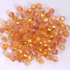 A pile of small, faceted, orange-colored glass beads shaped like bicones for jewelry making.