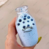 A hand holds a clear glass bottle filled with blue liquid and dark blue spherical toys labeled Chiboki