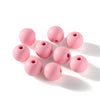 A collection of matte pink acrylic round beads scattered on a white surface.