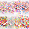 A collection of colorful polymer clay sprinkles in various shades scattered across a white background.
