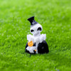 A white skull figure wearing a black top hat and holding a gold coin, set against bright green grass.