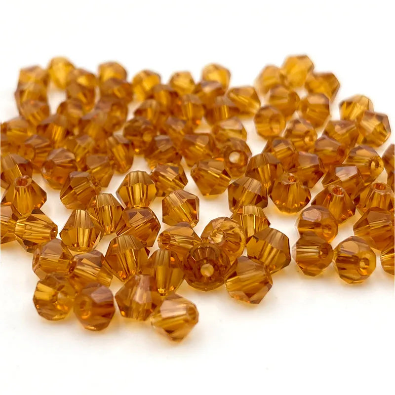 A pile of faceted bicone crystal glass beads in a golden amber color for jewelry making