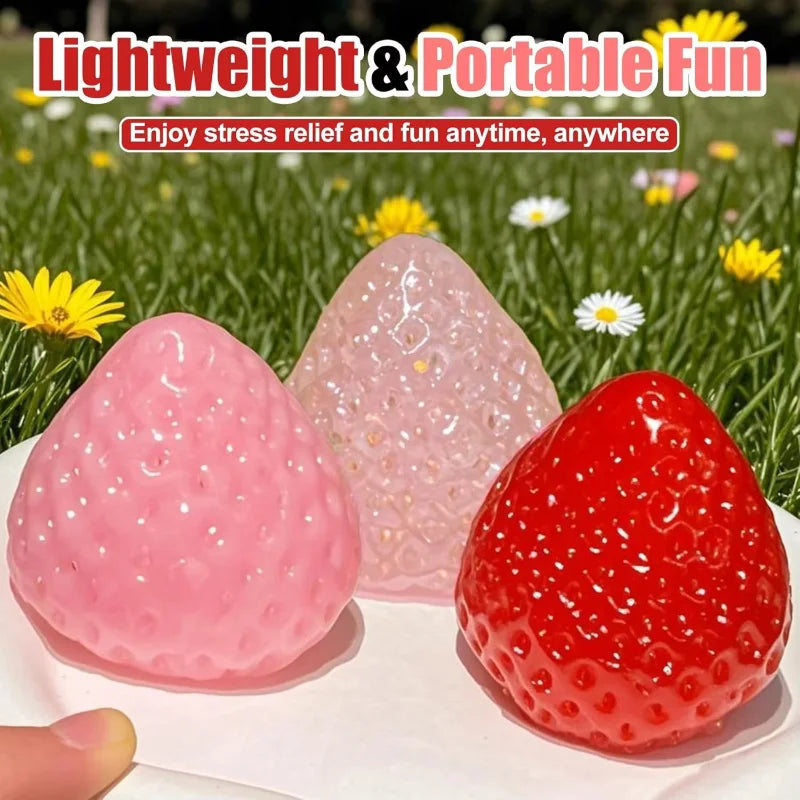 Three pink and red strawberry squishy fidget toys are displayed on a white surface.