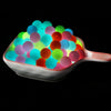 A white dish filled with glowing silicone beads of various colors including blue, green, pink, and orange.