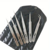 A set of six stainless steel precision tweezers with straight and bent tips resting on a dark leather surface.