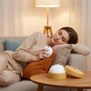 A woman rests her head on a sofa while holding an adorable dumpling squishy stress ball with a steamer basket.