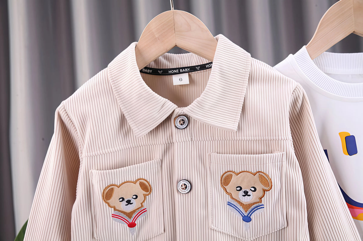 A light beige corduroy jacket for a child, featuring embroidered bear designs on the pockets.
